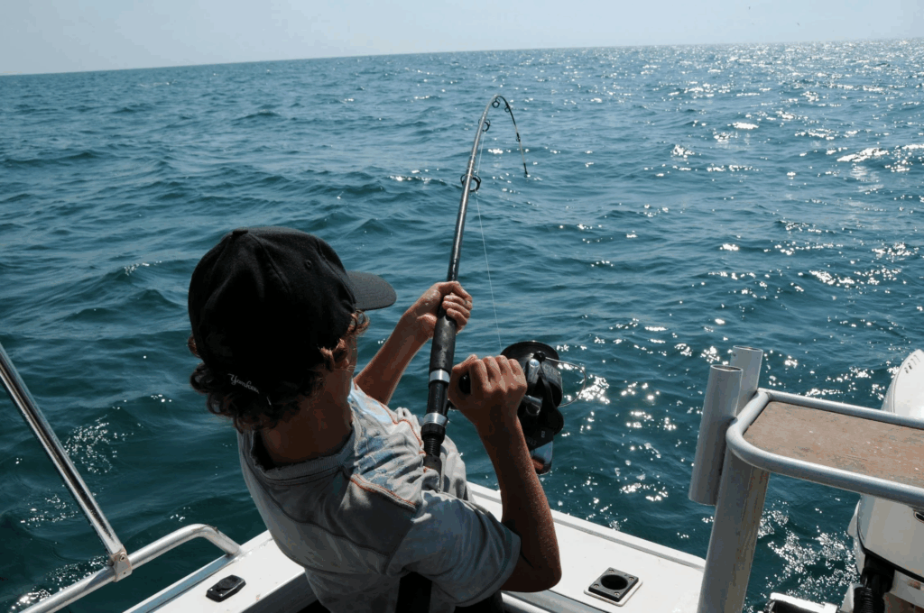 A person fishing from a boat in shimmering ocean waves, showcasing Costa Rica fishing.