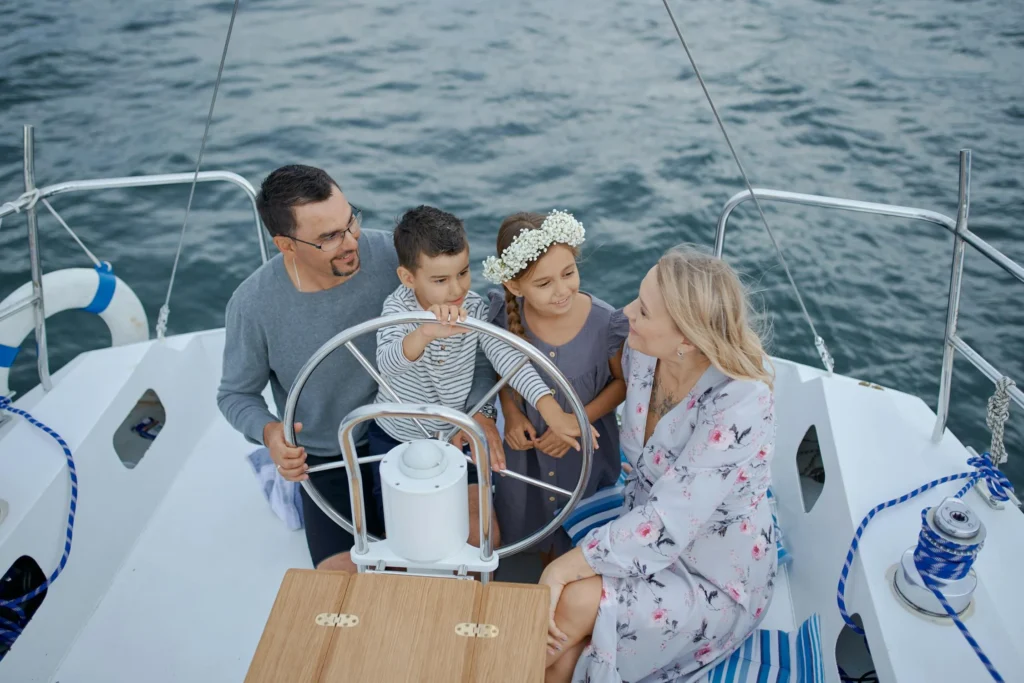 A family of four smiles on a sailboat, enjoying a day on the water and one of the many fun things to do in costa rica with kids.
