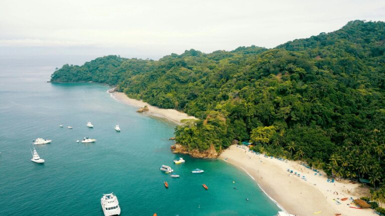 Aerial view of stunning Costa Rica beaches with lush rainforest, turquoise water, and boats dotting the coastline.