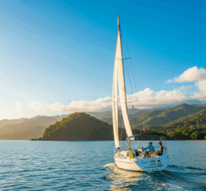 Sailboat cruising on calm waters near mountains, highlighting the beauty of sailing in Costa Rica.